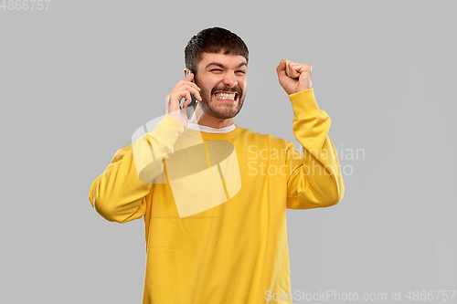 Image of happy smiling young man calling on smartphone