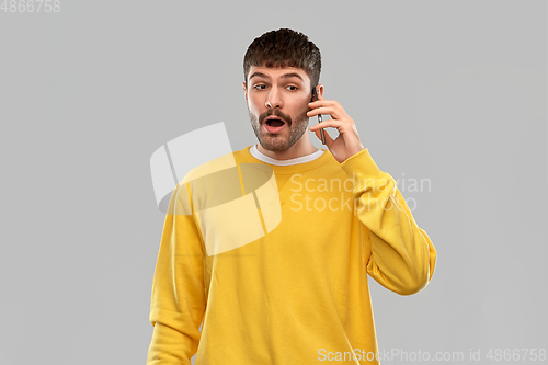 Image of shocked young man calling on smartphone