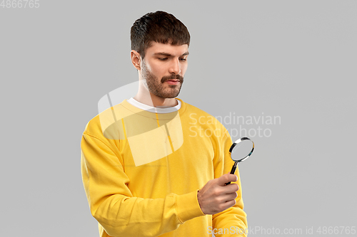 Image of man in yellow sweatshirt with magnifier