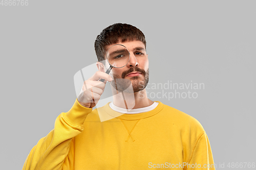 Image of man in yellow sweatshirt with magnifier