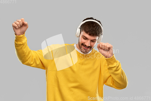 Image of happy smiling young man in headphones dancing