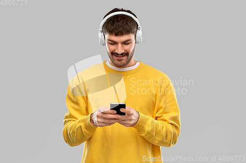 Image of smiling young man with headphones and smartphone