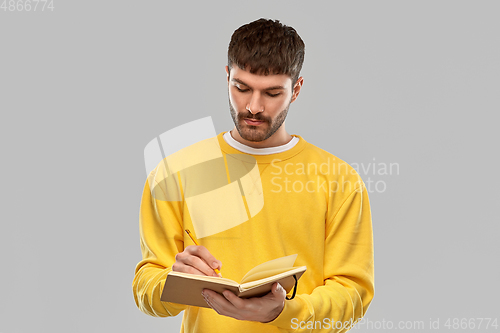 Image of man in yellow sweatshirt writing to diary