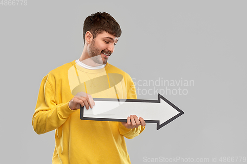 Image of smiling man holding big arrow pointing to right