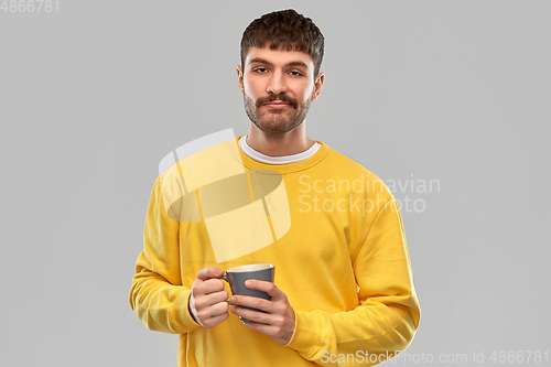 Image of displeased young man with coffee cup