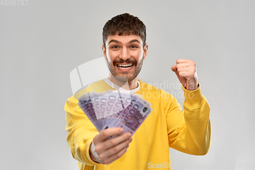 Image of happy young man with money celebrating success