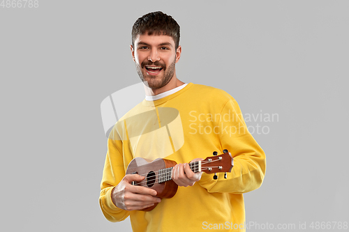 Image of smiling young man playing ukulele guitar