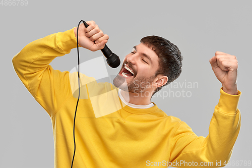 Image of man in yellow sweatshirt with microphone singing