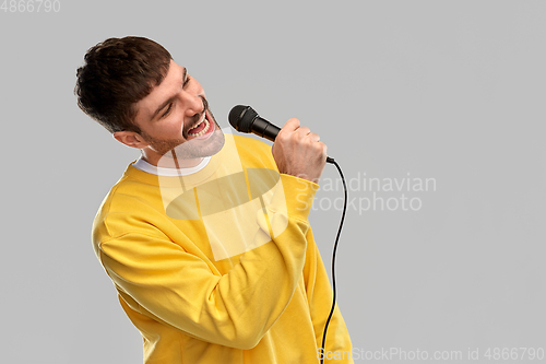 Image of man in yellow sweatshirt with microphone singing