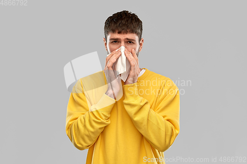 Image of man with paper napkin blowing nose