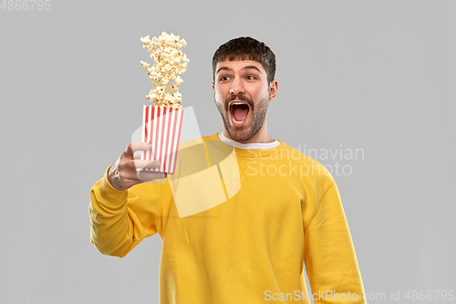 Image of man in yellow sweatshirt playing with popcorn