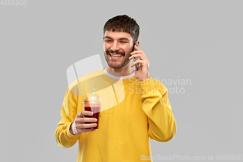 Image of happy man with tomato juice calling on smartphone