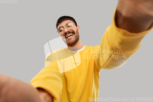 Image of happy young man in yellow sweatshirt making selfie