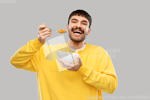 Image of happy smiling young man eating cereals