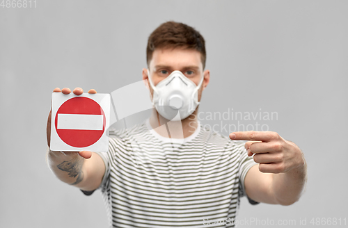 Image of man in respirator mask showing stop sign