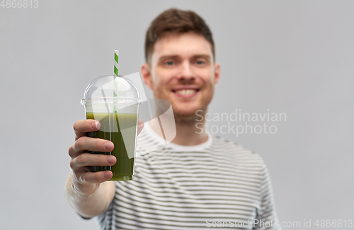 Image of man drinking green smoothie from disposable cup