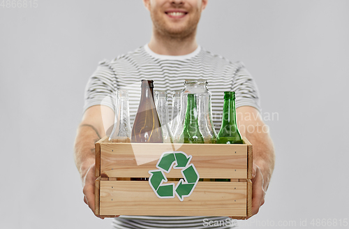 Image of smiling young man sorting glass waste