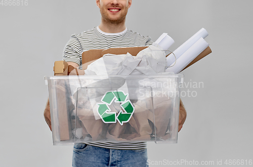 Image of smiling young man sorting paper waste