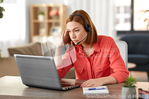 Image of sad woman with headset and laptop working at home