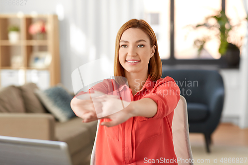 Image of happy woman stretching arms at home office