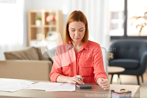 Image of woman with calculator and papers working at home