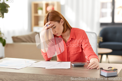 Image of woman with calculator and papers working at home