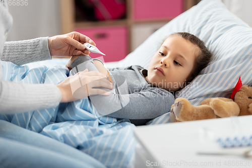 Image of mother measuring temperature of sick daughter