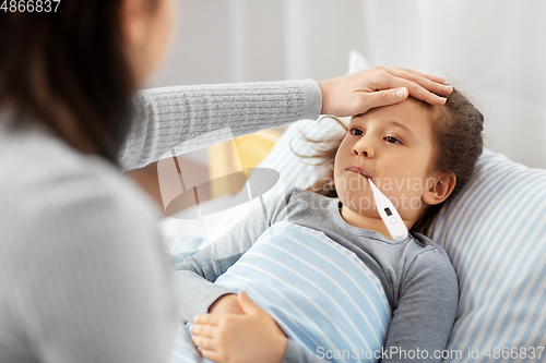 Image of mother and sick daughter measuring temperature