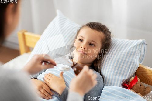 Image of mother pouring cough syrup for sick daughter