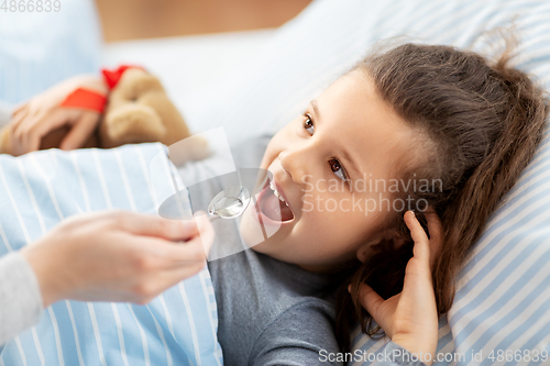 Image of mother giving cough syrup to sick daughter