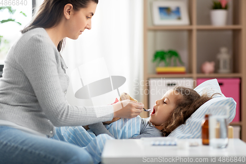 Image of mother giving cough syrup to sick daughter