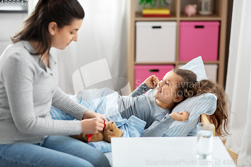 Image of mother and happy little daughter in bed at home