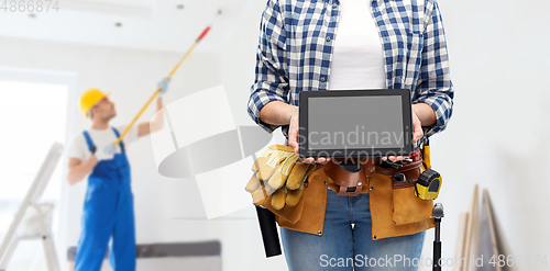Image of woman builder with working tools showing tablet pc