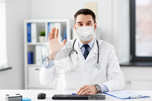 Image of happy male doctor waving hand at hospital
