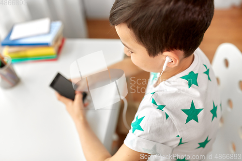 Image of boy with earphones and smartphone at home