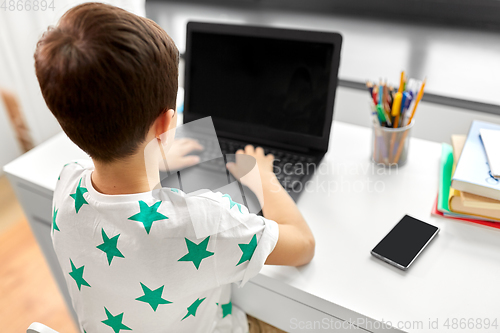 Image of student boy typing on laptop computer at home