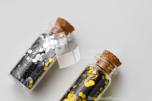 Image of silver and gold glitter in bottles on white