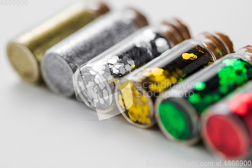 Image of set of glitters in bottles over white background