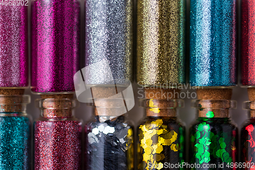 Image of set of different glitters in small glass bottles