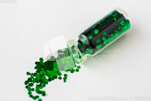 Image of green glitters poured from small glass bottle