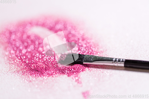 Image of make up brush making stroke on pink glitters