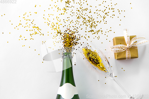 Image of champagne bottle, glass, gift and golden glitters
