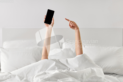 Image of hands of woman lying in bed with smartphone