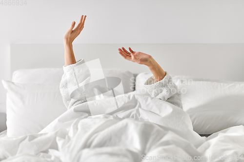 Image of hands of woman lying in bed and stretching