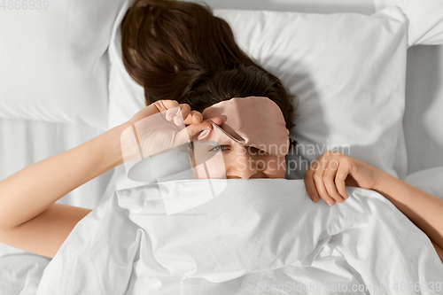 Image of woman with eye sleeping mask in bed under blanket