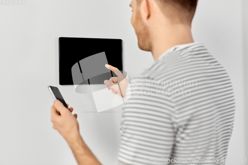 Image of man with smartphone and tablet pc at smart home