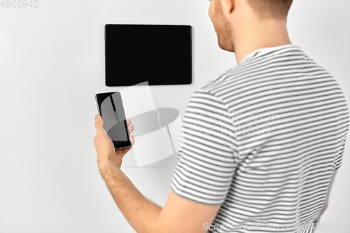 Image of man with smartphone and tablet pc at smart home