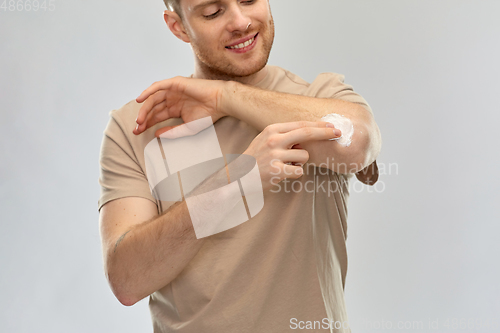 Image of young man applying pain medication to his elbow