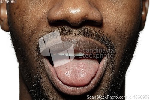 Image of Close up of face of beautiful african-american young man, focus on mouth, stick out tongue