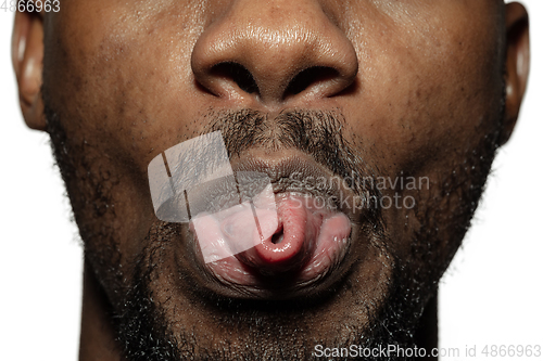Image of Close up of face of beautiful african-american young man, focus on mouth, stick out tongue